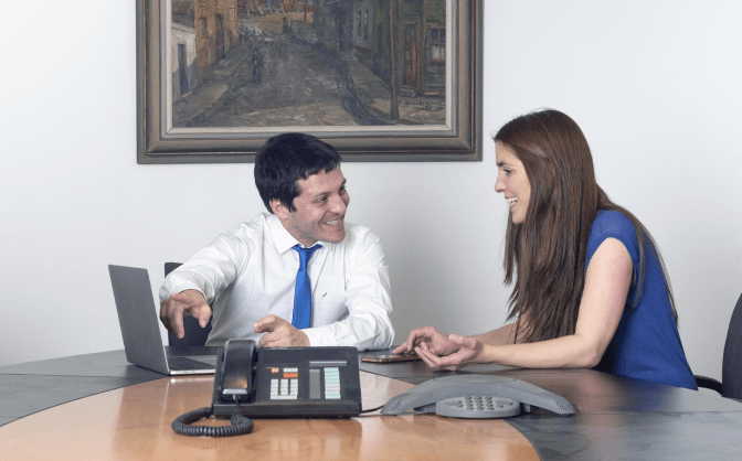 Foto de un hombre y una mujer reunidos en una oficina haciendo la vinculación en banca de inversión en Valores Bancolombia por medio del computador portátil del hombre.